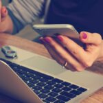 Person sidder med en smartphone og laptop