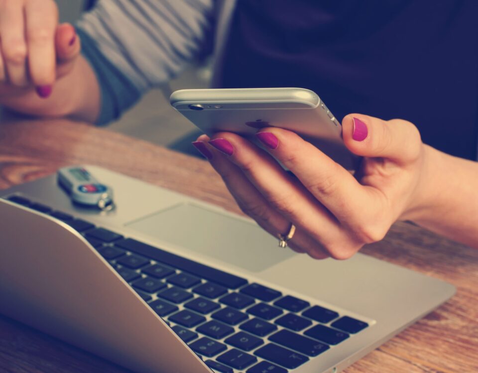 Person sidder med en smartphone og laptop
