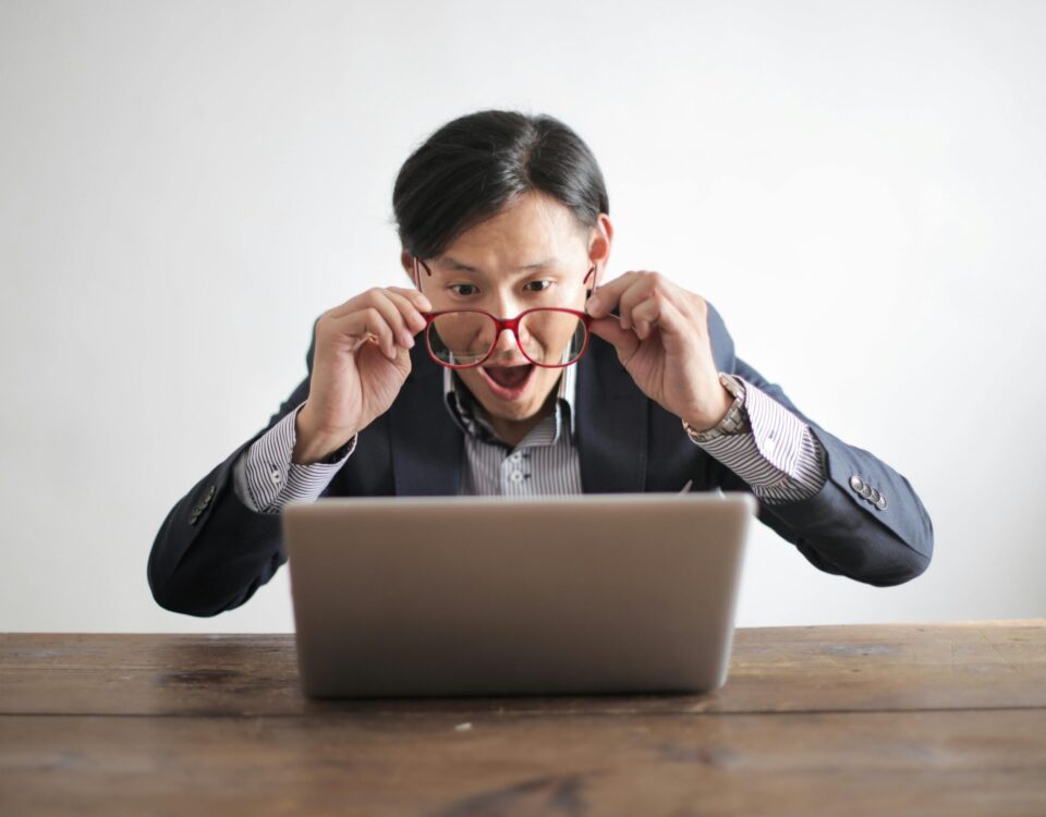 Man with glasses looking suprised at his laptop